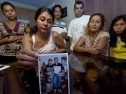 Patricia Villanueva tient une photo de son frère, Freddy, entourée par les membres de la famille.