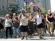 Des manifestants contre les compressions d'Ottawa en culture marchent dans la rue.