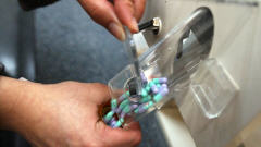 Un pharmacien transf�re des m�dicaments dans un tube.