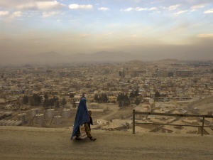 Une femme et son enfant marchent sur une route surplombant Kaboul.