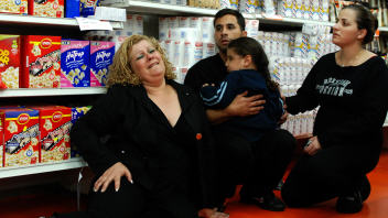Des Isra�liens qui se trouvaient � l'int�rieur d'un magasin, � Sderot, atteint par une roquette palestinienne.
