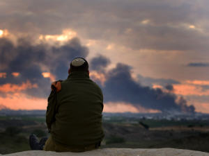 Un soldat israélien observe la fumée dégagée à la suite d'un raid, à la frontière entre Israël et la bande de Gaza