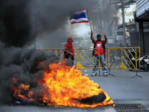 Un manifestant brandit un drapeau thaïlandais derrière un pneu qui brûle à Bangkok, en Thaïlande