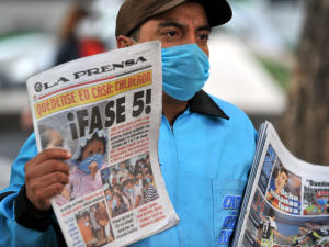 Vendeur de journaux, protégé par un masque, à Mexico.