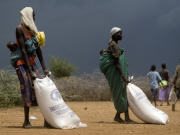 Des Ougandaises prenant possession de sacs de farine fournis par le Programme alimentaire mondial
