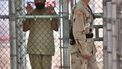 Un militaire passe devant un prisonnier en cellule à la prison militaire américaine de Guantanamo Bay.