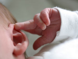 Un bébé se met le doigt dans l'oreille