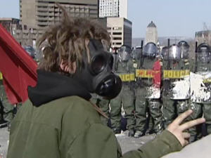 Un manifestant au Sommet des Amériques, à Québec, face à des policiers antiémeutes.