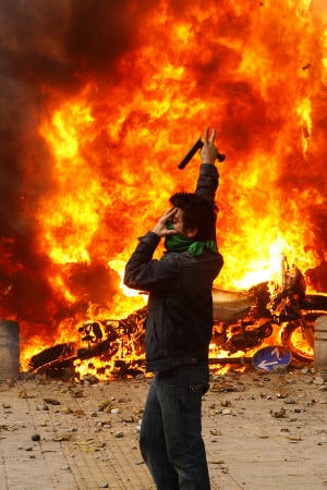Un militant de l'opposition à Téhéran devant des motos de la police en feu.