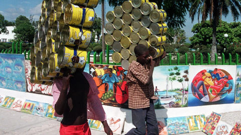 De jeunes Haïtiens transportent des boîtes vides qui seront recyclées pour en faire des casseroles. (archives)