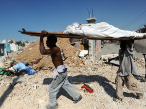 Au milieu des décombres, des Haïtiens portent un cadavre pour l'enterrer dans une fosse commune à Port-au-Prince.