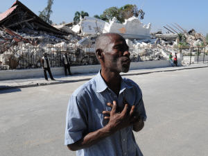 Un Haïtien prie devant l'édifice qui abritait le ministère de la Justice.