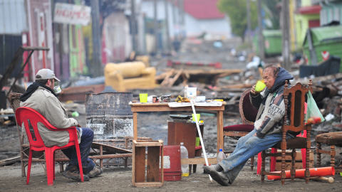 Deux hommes assis dans une rue d�vast�e de Talcahuano, apr�s le s�isme de magnitude 8,8.