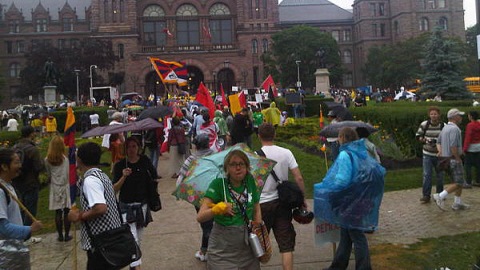 Des manifestants devant Queen's Park affrontent la pluie.