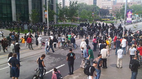 Des manifestants devant un barrage policier sur College Street