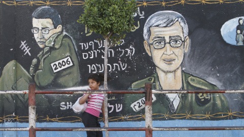 Une jeune Palestinienne devant une murale repr�sentant le soldat Gilad Shalit jeune (� gauche) et vieux (� droite)