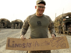 Un militaire tient une pancarte sur laquelle on peut lire: « Lindsay et Austin: papa rentre à la maison. »