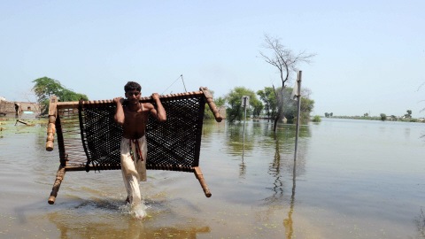 Un homme transporte son lit dans une zone inond�e du sud du Pakistan