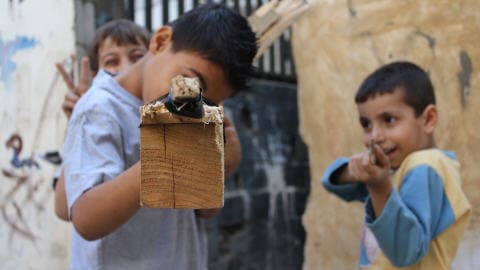 Des enfants de Chatila pointent leur armes en bois, leurs seuls jouets.  