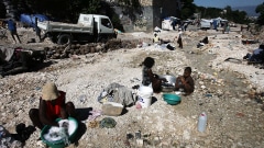 Installées dans les débris, des femmes nettoient leurs vêtements près de Port-au-Prince.