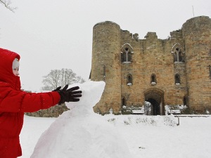 Un enfant fait un bonhomme de neige dans le sud-est de l'Angleterre.