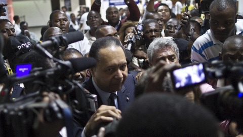 Jean-Claude Duvalier entouré de journalistes à son arrivée à l'aéroport