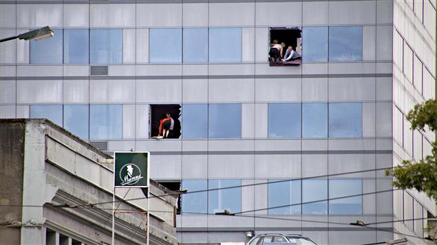Des employés brisent des fenêtres pour accueillir les secours qui viendront en échelles.
