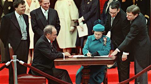 Signature de la Constitution canadienne par la reine Elizabeth II à Ottawa, le 17 avril 1982, en présence du premier ministre Pierre Trudeau