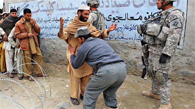 Un policier afghan effectue une fouille corporelle à Khogiani devant un soldat américain
