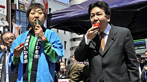 Le secrétaire en chef du cabinet, Yukio Edano (à droite), et le comédien Shizu-chan croquent à pleines dents dans des légumes en provenance de Fukushima, dans un marché de Tokyo, le 12 avril 2011. Ils veulent ainsi encourager les agriculteurs qui subissent les contrecoups de l'accident nucléaire.
