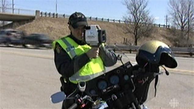 Un policier de la police provinciale de l'Ontario utilise un radar pour évaluer la vitesse d'une voiture. Archives.