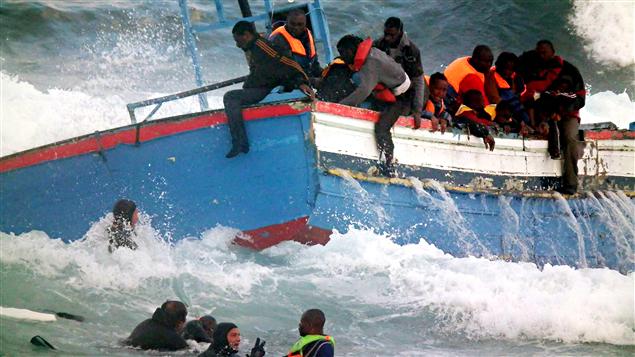Una embarcación transportando inmigrantes que zarparon de Libia, es socorrida por un barco frente a la costa italiana.