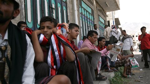 Des Yéménites lisent les informations sur un trotoir, à Taëz.