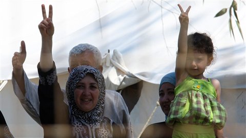 Des réfugiés syriens font le signe de la victoire depuis un camp du Croissant rouge en Turquie. Le gouvernement turc empêche les journalistes de parler à ces réfugiés, qui ont pourtant des témoins privilégiés de la situation qui prévaut en Syrie.