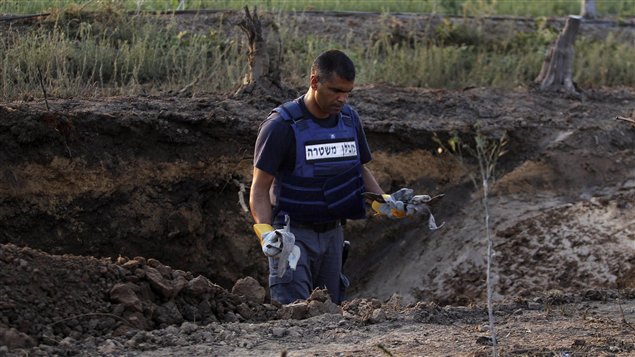 Un policier israélien inspecte les restes d'une roquette tombée près de la ville portuaire d'Ashdod, dans le sud d'Israël.