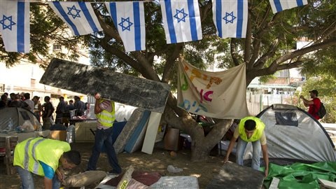 Des inspecteurs municipaux accompagnés par les forces de police démantèlent des structures de bois bâties par les manifestants dans la ville de Holon, au sud de Tel-Aviv.