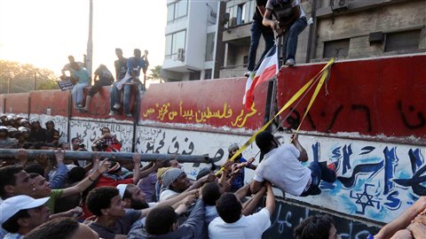 Des manifestants tentent de jeter à terre un mur de protection érigé récemment près de l'ambassade israélienne.