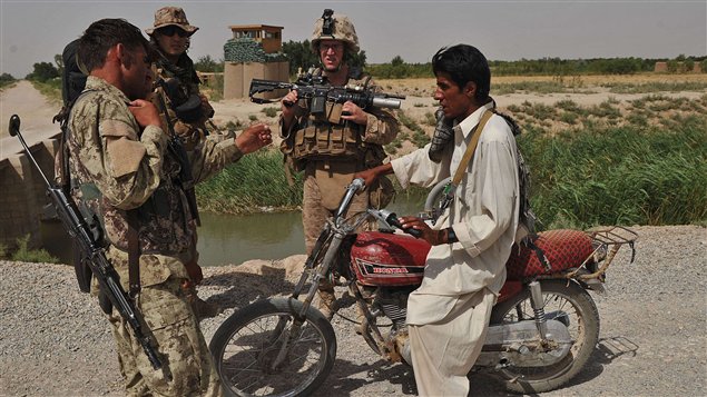 Des marines américains vérifient l'identité d'un membre de la Police locale afghane dans la province de Helmand.