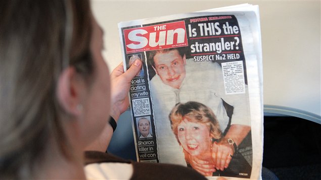 Une femme lit la une du journal « Sun » à Londres (archives)