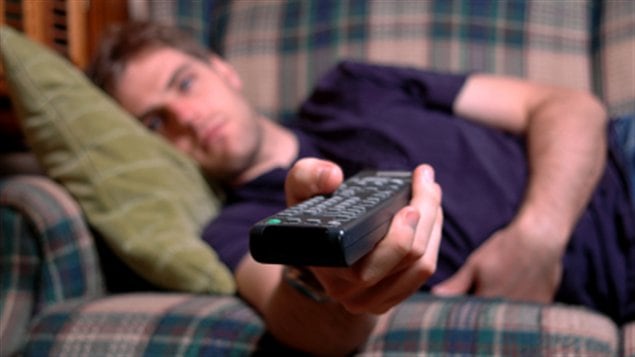 Un homme étendu sur un divan pour regarder la télévision