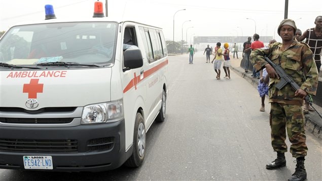 Une ambulance circule près d'un policier nigérian, le 16 janvier.