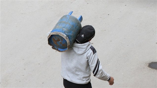 Un syrien transportant une bonbonne de gaz près de Damas