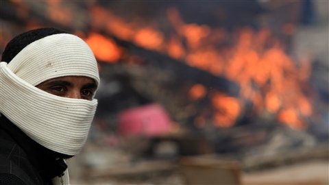Un manifestant masqué devant un feu près du ministère de l'Intérieur, au centre du Caire, vendredi