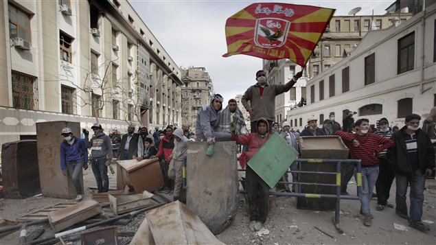 Des partisans tentent de bloquer une rue près du ministère de l'Intérieur. Au centre, un homme brandit le drapeau du club d'Al-Ahly.