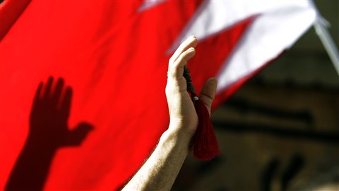 Un manifestant brandit le drapeau du pays lors des funérailles d'une femme à Manama en mars 2011.