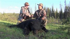 Des chasseurs devant un ours abattu