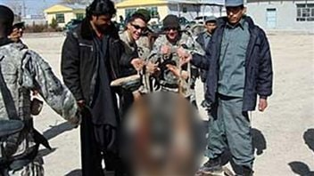 Des soldats américains et des membres des forces afghanes posent avec les restes d'un kamikaze.