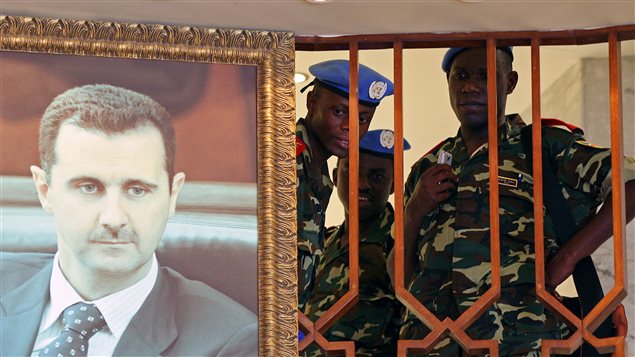 Membres de la mission de l'ONU à Damas à côté d'une affiche représentant Bachar Al-Assad.