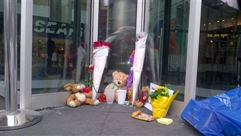 Des fleurs et des ours en peluche, devant une entrée du Centre Eaton, lundi matin.