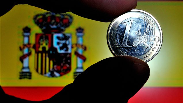 Une pièce de 1 euro, avec, en arrière-fond, le drapeau espagnol